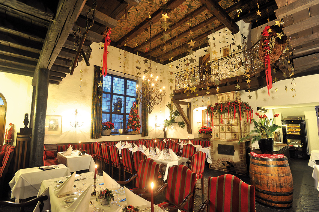 Geschmückter Speisesaal eines Restaurants mit gestreiften Stühlen, festlicher Dekoration und Tischen mit Kerzenlicht.